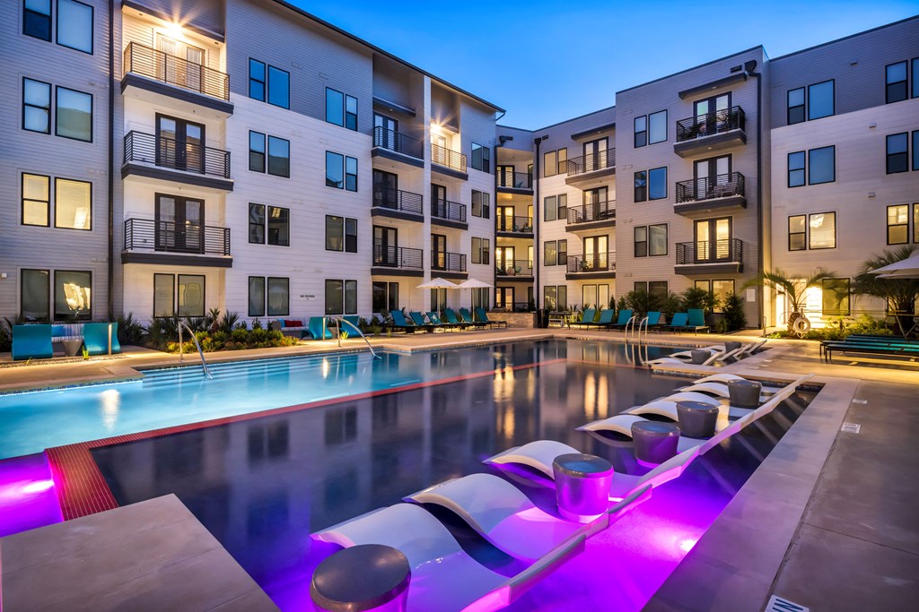 an apartment building with a pool and lounge chairs