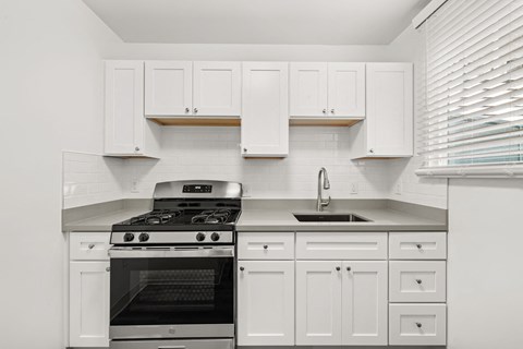 A modern kitchen with white cabinets and a stainless steel stove.