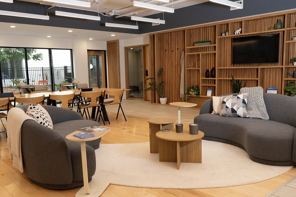 A living room with a grey couch, a wooden coffee table, and a TV on a wooden stand.