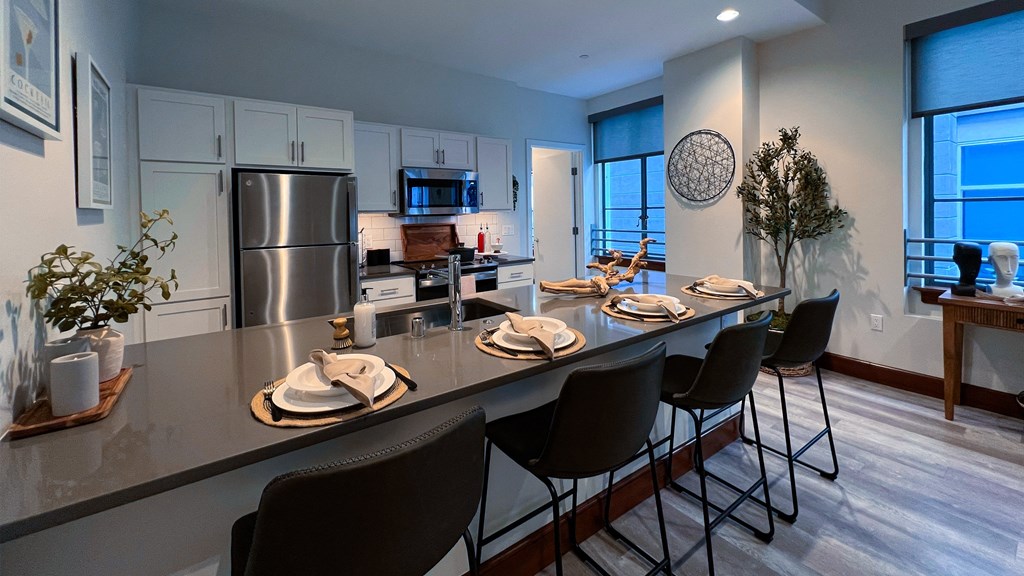 an open kitchen and dining area with stainless steel appliances and a long counter with chairs