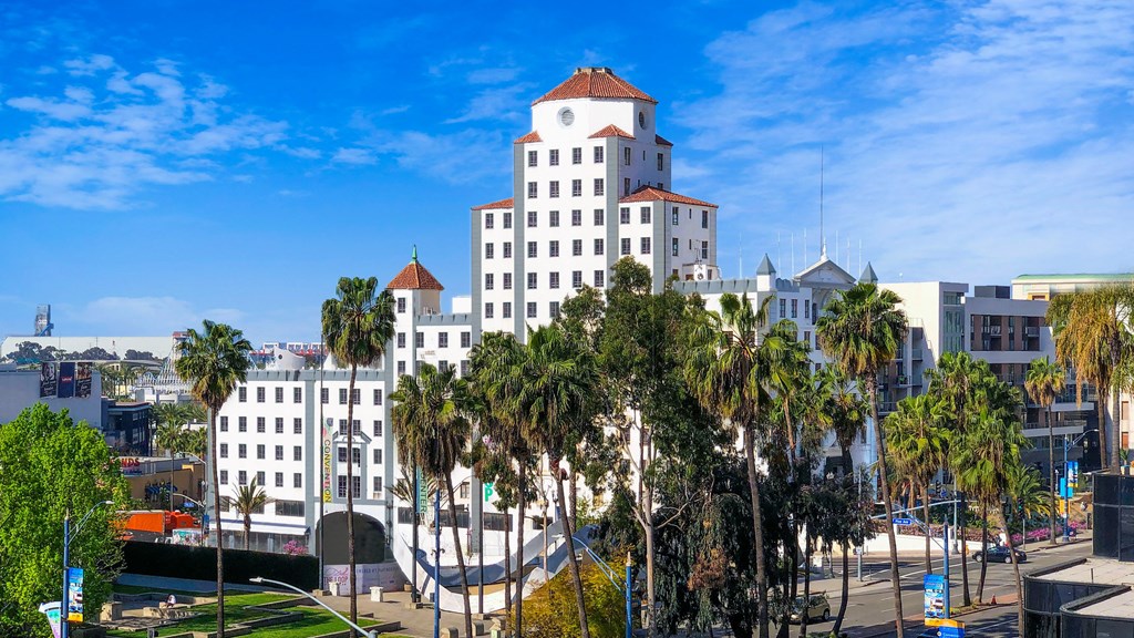 a large white building with a red roof and palm trees