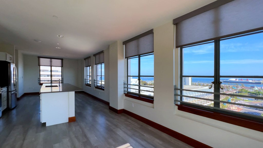 an empty living room with large windows and a view of the city