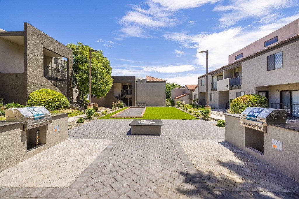 a courtyard between two buildings with a green lawn and benches
