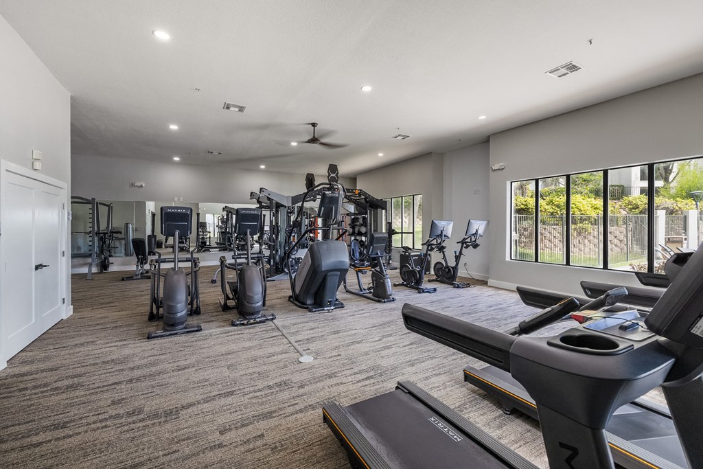 the fitness center has cardio machines and treadmills and a large window