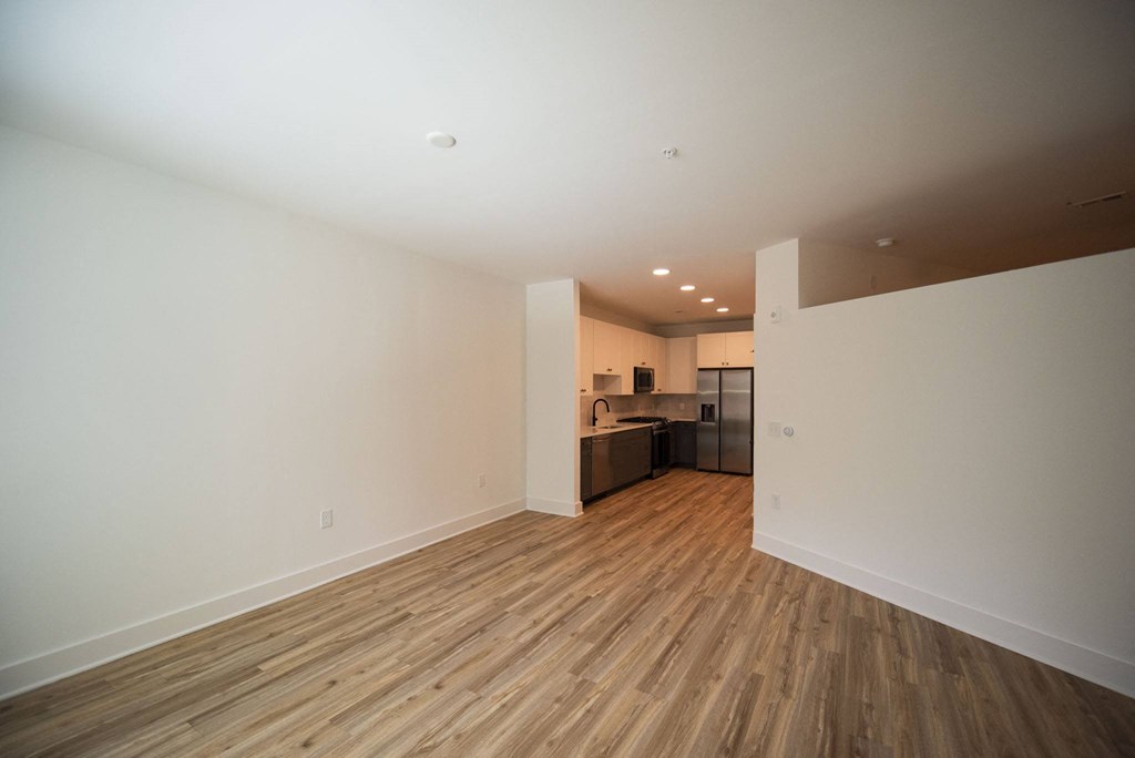 a living room and kitchen with wood floors and white walls