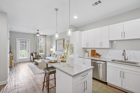 A kitchen with white cabinets and a marble countertop.
