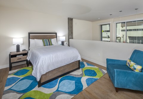 A bedroom with a white bed and a blue chair.