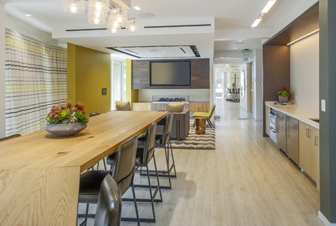 A modern kitchen with a long wooden table and chairs.