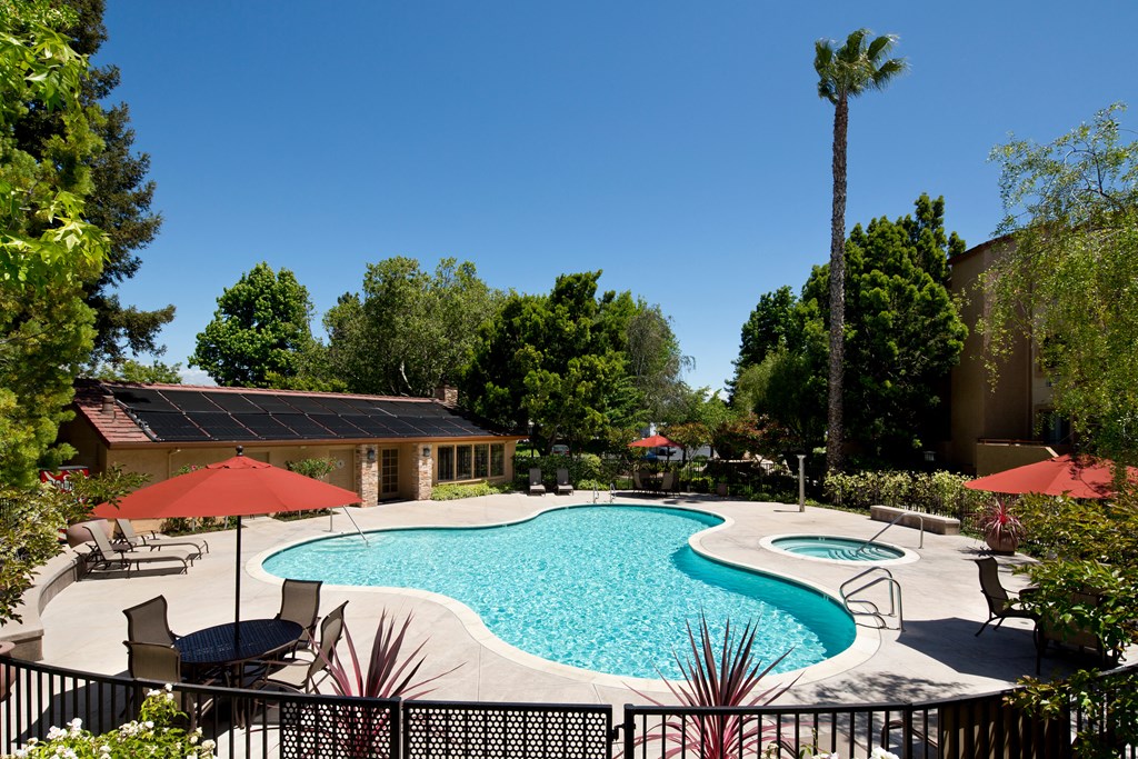 Apartments in Sunnyvale, CA for Rent - mResidences Silicon Valley - Pool Area with Fenced in Area, Surrounded by Trees and Landscaped Greenery, with Poolside Seating, Tables, and Umbrellas