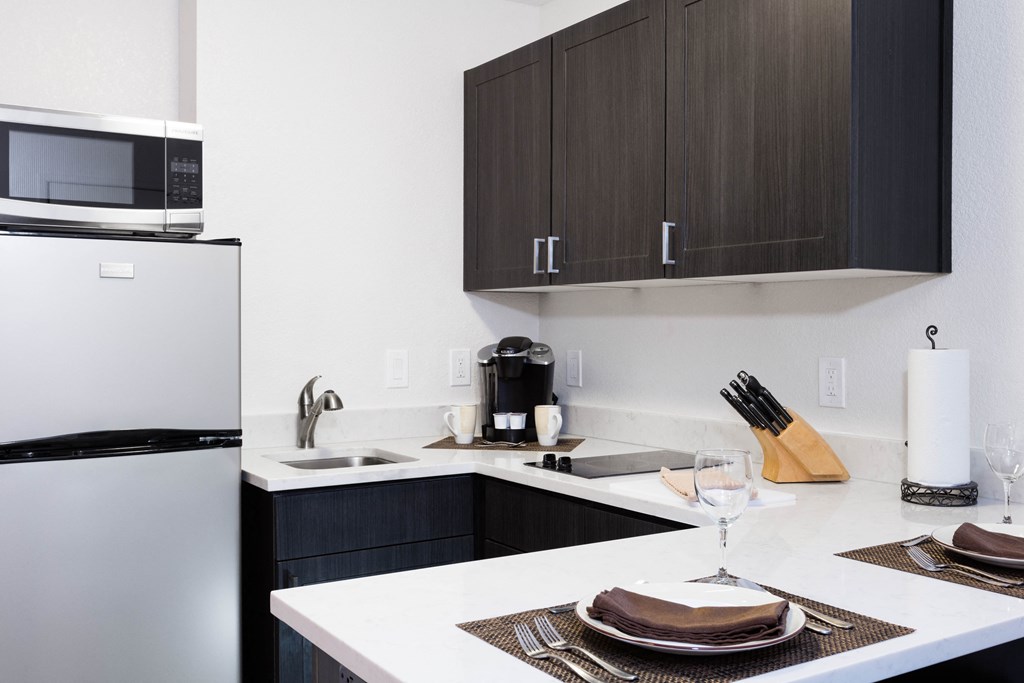 Apartments in Sunnyvale CA - mResidences Silicon Valley - Kitchen with White Walls, Silver Appliances, Dark Brown Cabinets, Silver Hardware, and White Counters