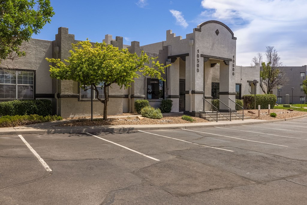 a building with a parking lot and a tree in front of it