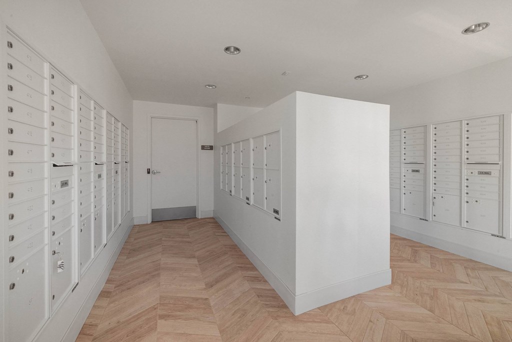 A hallway with a white wall and a wooden floor.