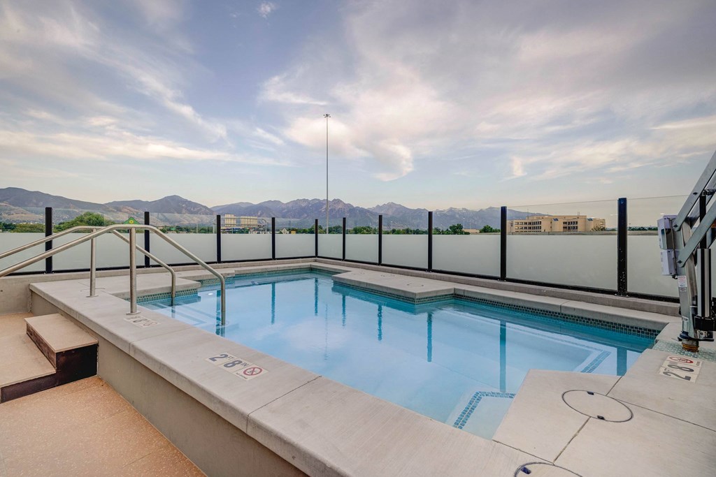 A small indoor pool with a glass railing and a mountain view.