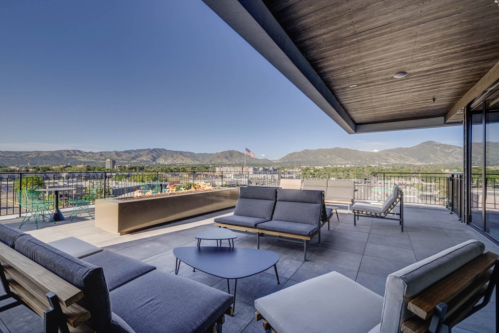 A patio with a table and chairs overlooking a mountain range.