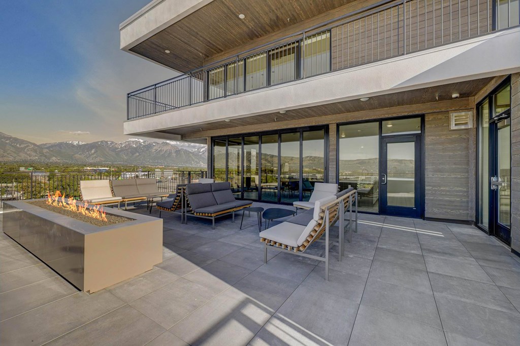 A modern patio with a fire pit and seating area.