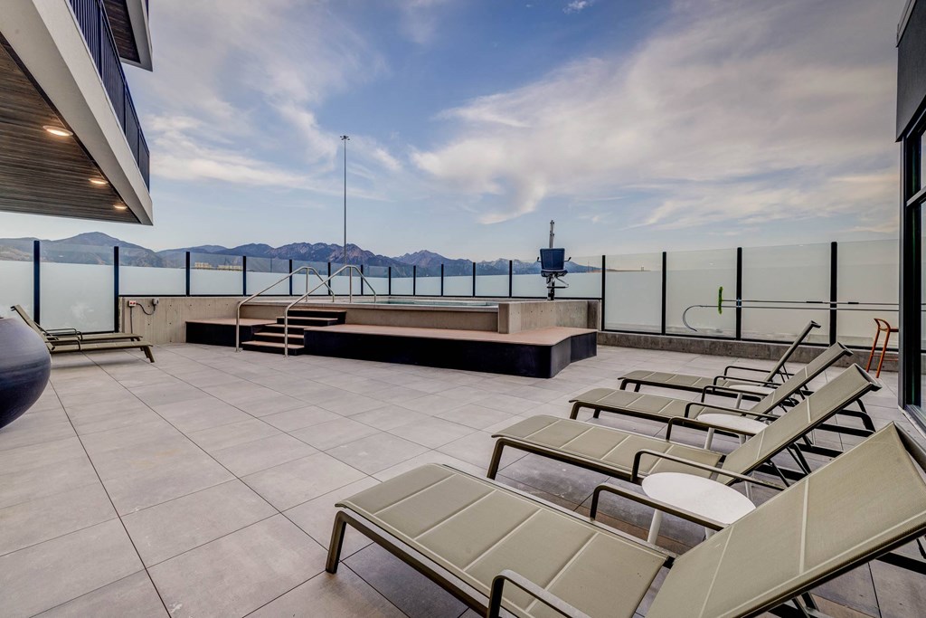 A rooftop patio with sun loungers and a view of the mountains.