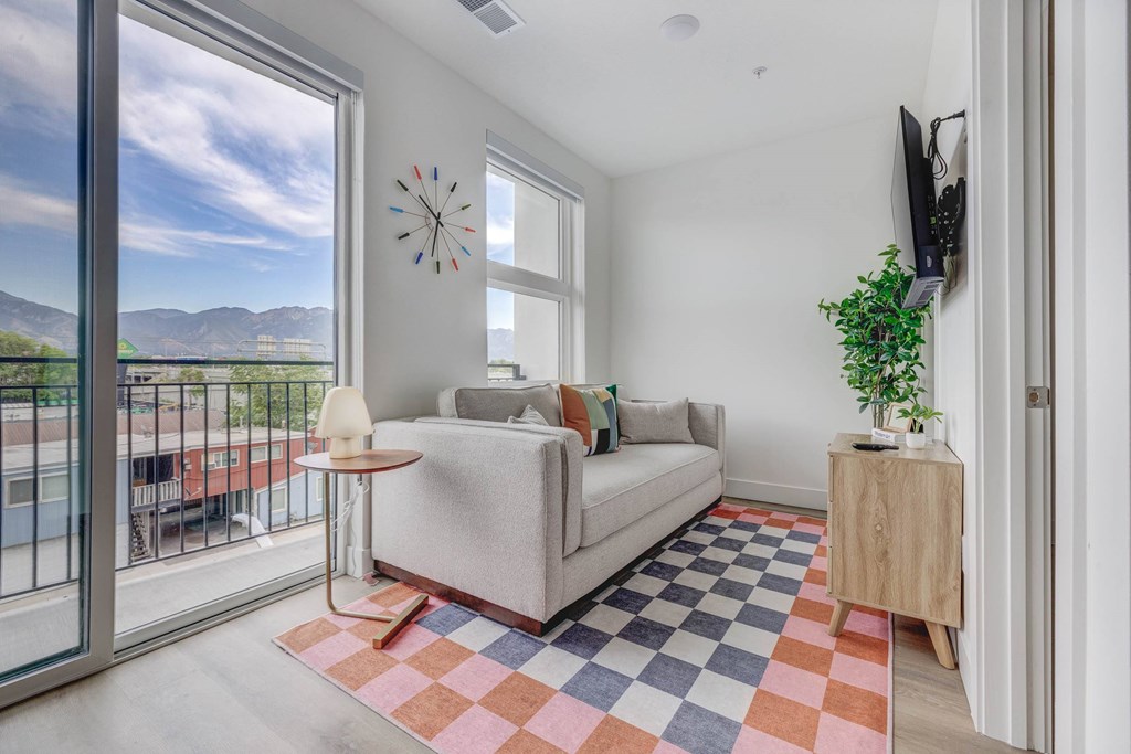 A living room with a couch, a table, a plant, and a TV.