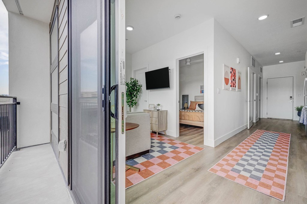 A modern living room with a white interior and a glass door leading to a balcony.
