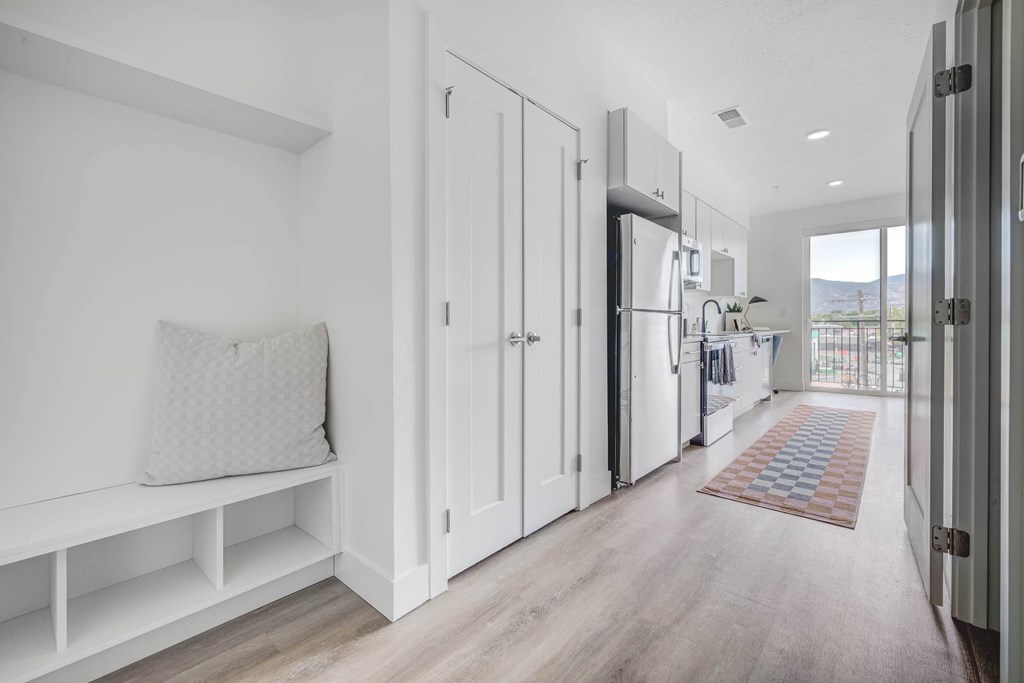 A white kitchen with a bench and a rug on the floor.