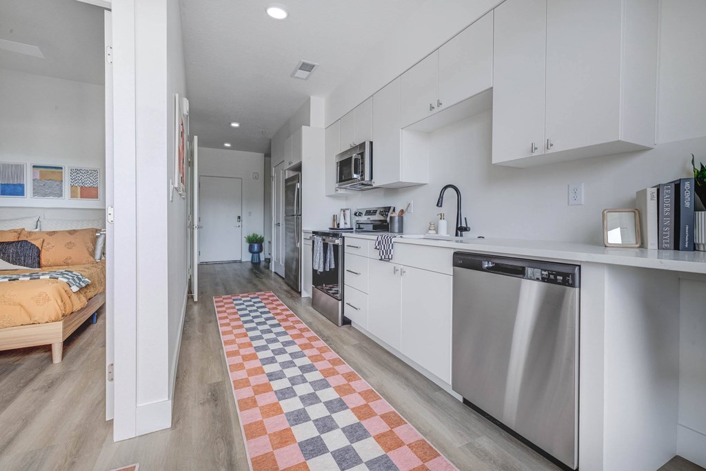 A kitchen with a checkered rug on the floor.