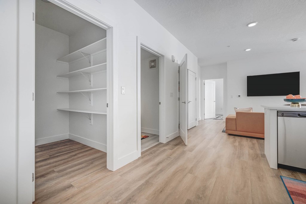 A kitchen with a refrigerator, a sink, and a countertop with a black screen on the wall.