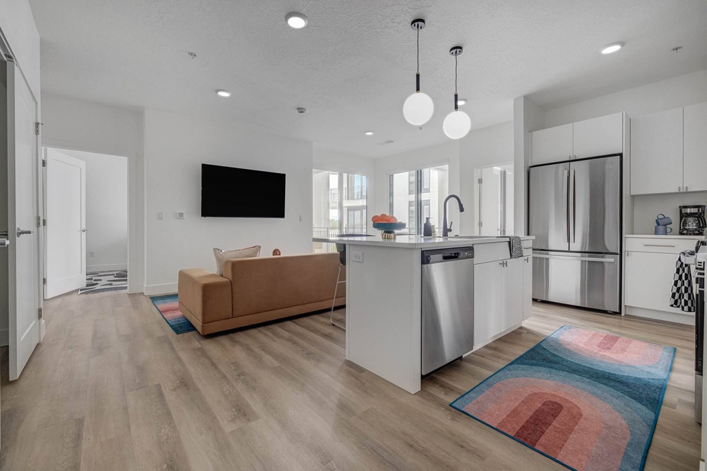 A modern kitchen with a brown sofa and a flat screen TV mounted on the wall.