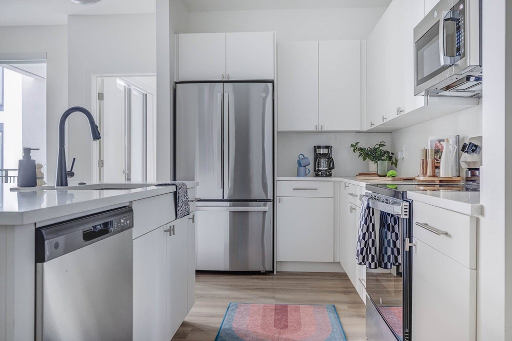A modern kitchen with white cabinets and stainless steel appliances.