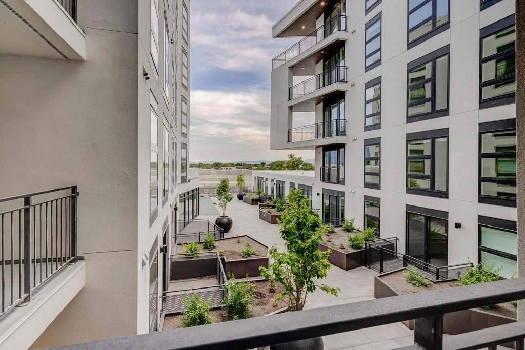 A balcony with a view of a building and a tree.