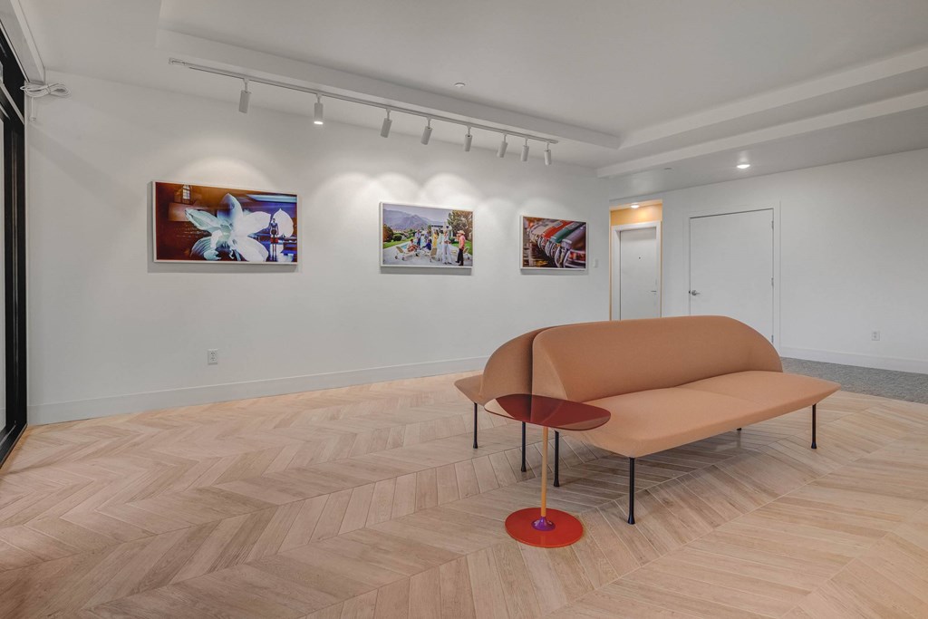 A room with a tan couch and a red table.