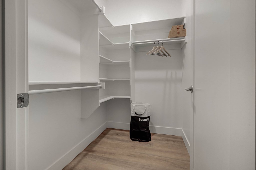 A white closet with a bag of laundry on the floor.