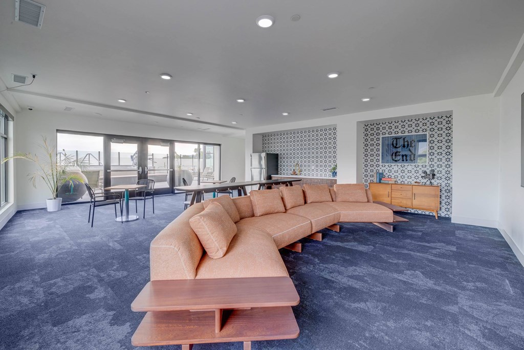 A long wooden table with a bench in front of a grey carpet.