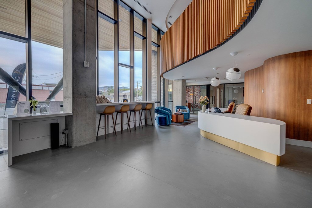 A reception area with a white counter and orange chairs.