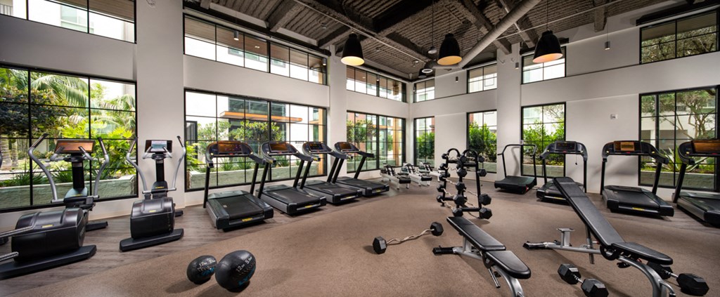 a gym with cardio equipment and windows in a building