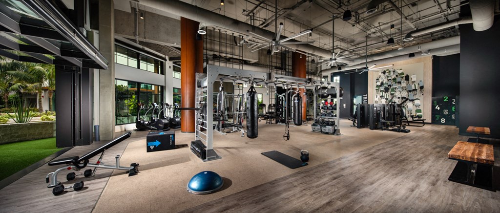 a workout room with weights and other exercise equipment in a building with windows