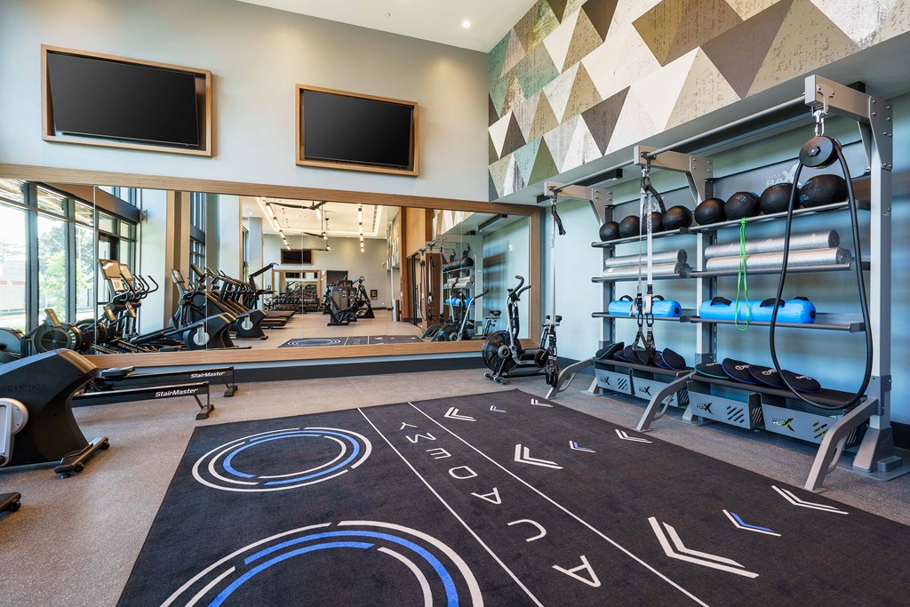 a gym with weights and weights on a floor and a wall of windows