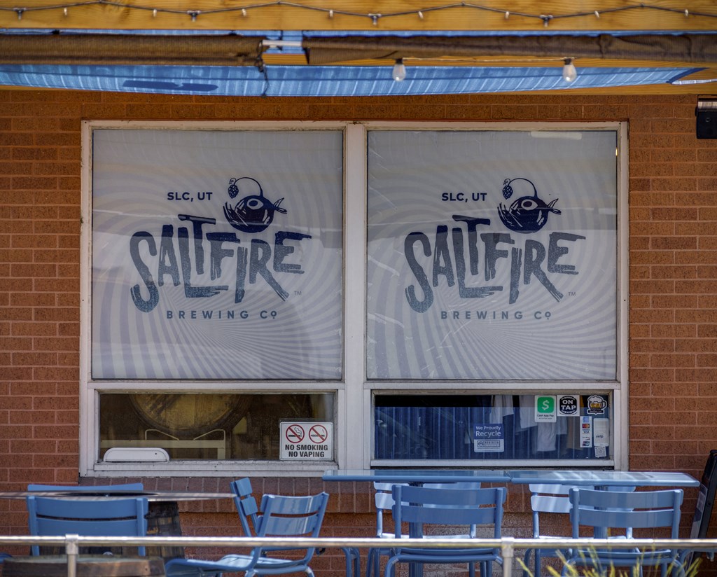 Saltfire Brewing Co. logo on a window with blue chairs outside.