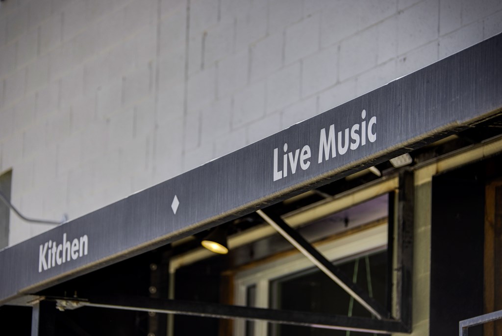 A sign that says Live Music is hanging from the side of a building.