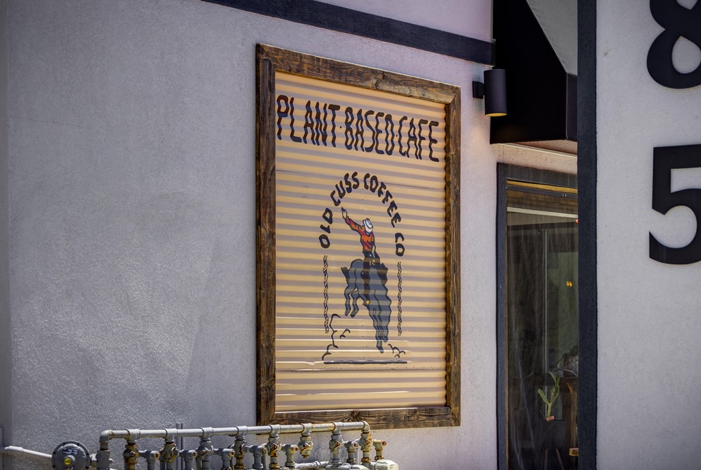 A sign for a plant-based cafe is hanging on a wall.