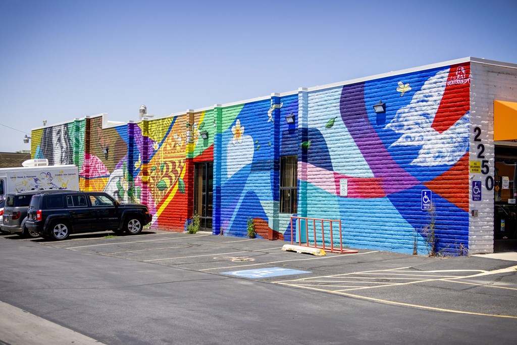 A colorful mural on a building with a car parked in front.