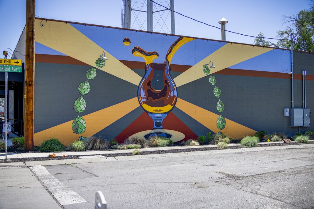 A mural of a bird with green leaves around its neck is painted on a wall.