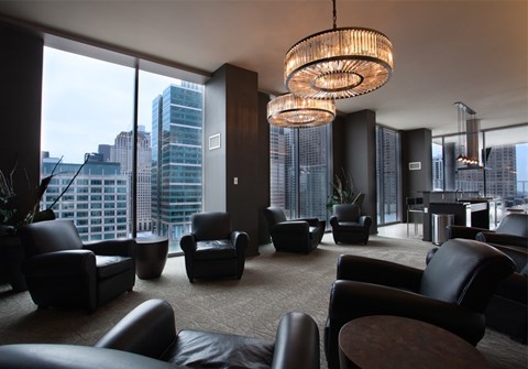 A modern living room with black leather furniture and a large window overlooking the city.