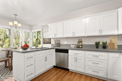 A kitchen with white cabinets and a wooden floor.