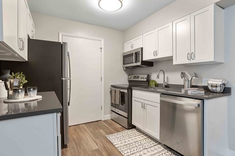 A kitchen with a black refrigerator and stainless steel appliances.