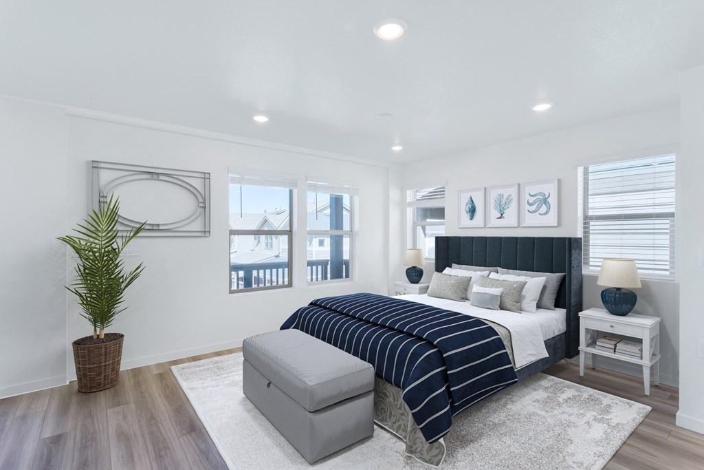 a white bedroom with a blue bed and a large potted plant