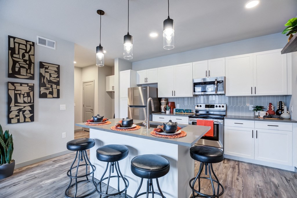 an open kitchen with a breakfast bar and stools in front of a kitchen island
