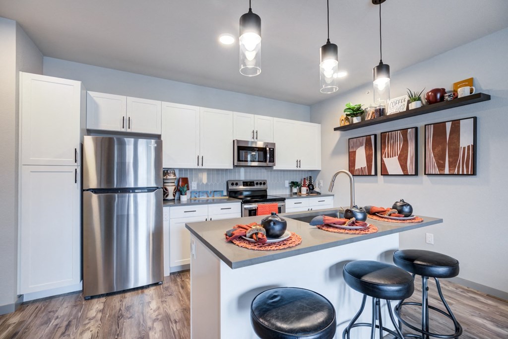 a kitchen with a center island and stainless steel refrigerator