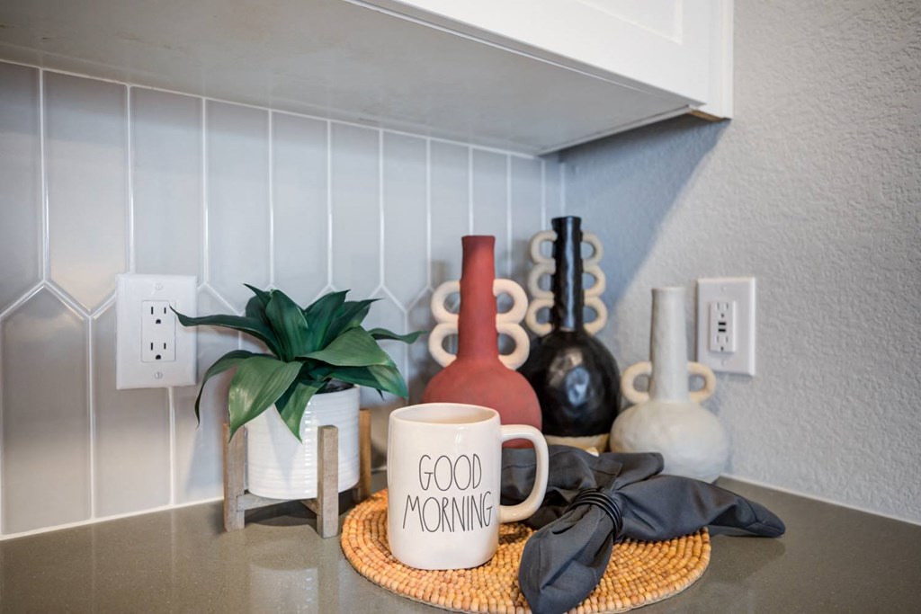 a coffee mug on a counter with a plant and other items
