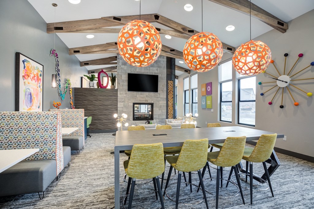 a communal table in a community room with chairs and lamps