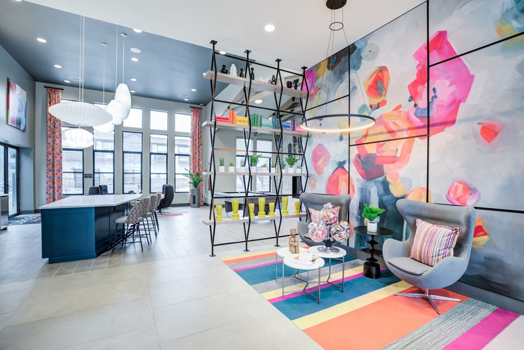 a living room with chairs and a table and a large painting on the wall