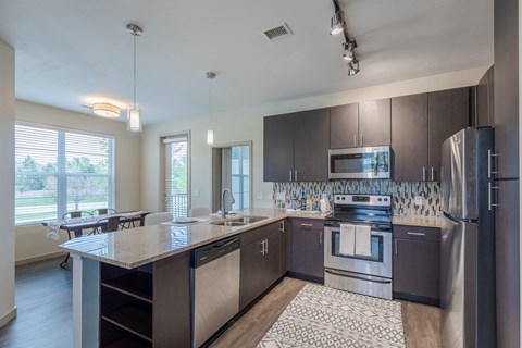 an open kitchen with stainless steel appliances and a granite counter top